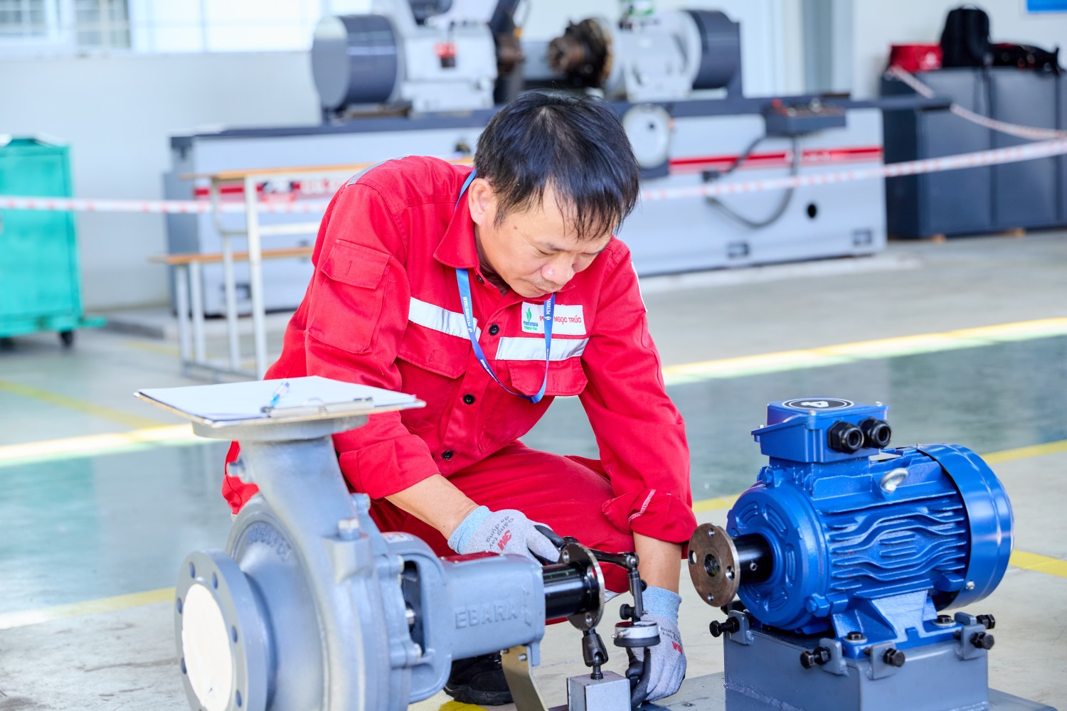 Thí sinh sử dụng đồng hồ so để kiểm tra độ đồng tâm, đánh giá độ lệch giữa trục động cơ điện và trục bơm ly tâm. Đây là công đoạn quan trọng trong quá trình căn chỉnh đồng trục, đòi hỏi người thợ phải thực hiện chính xác các thao tác đo đạc, ghi nhận thông số và xác định mức độ sai lệch so với yêu cầu kỹ thuật. Nếu hai trục không được căn chỉnh phù hợp, thiết bị có thể phát sinh rung động, tiếng ồn, gia tăng tải trọng lên ổ đỡ và khớp nối, từ đó ảnh hưởng đến tuổi thọ cũng như hiệu quả vận hành của hệ thống.